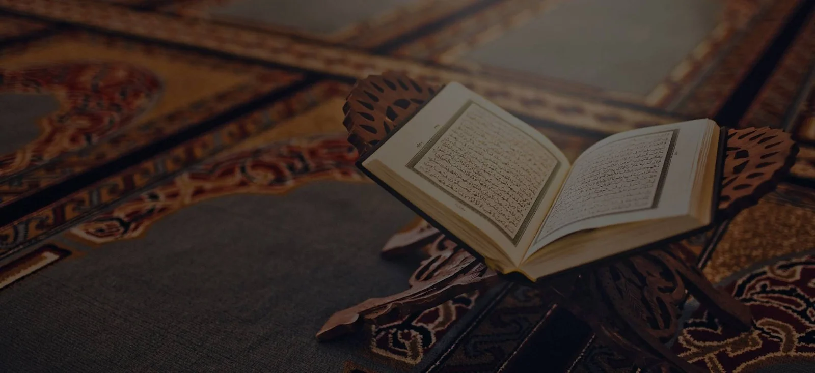 An open Quran resting on a carved wooden stand inside a masjid